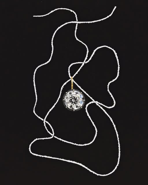 An old European cut diamond pendant on a looping chain, on black